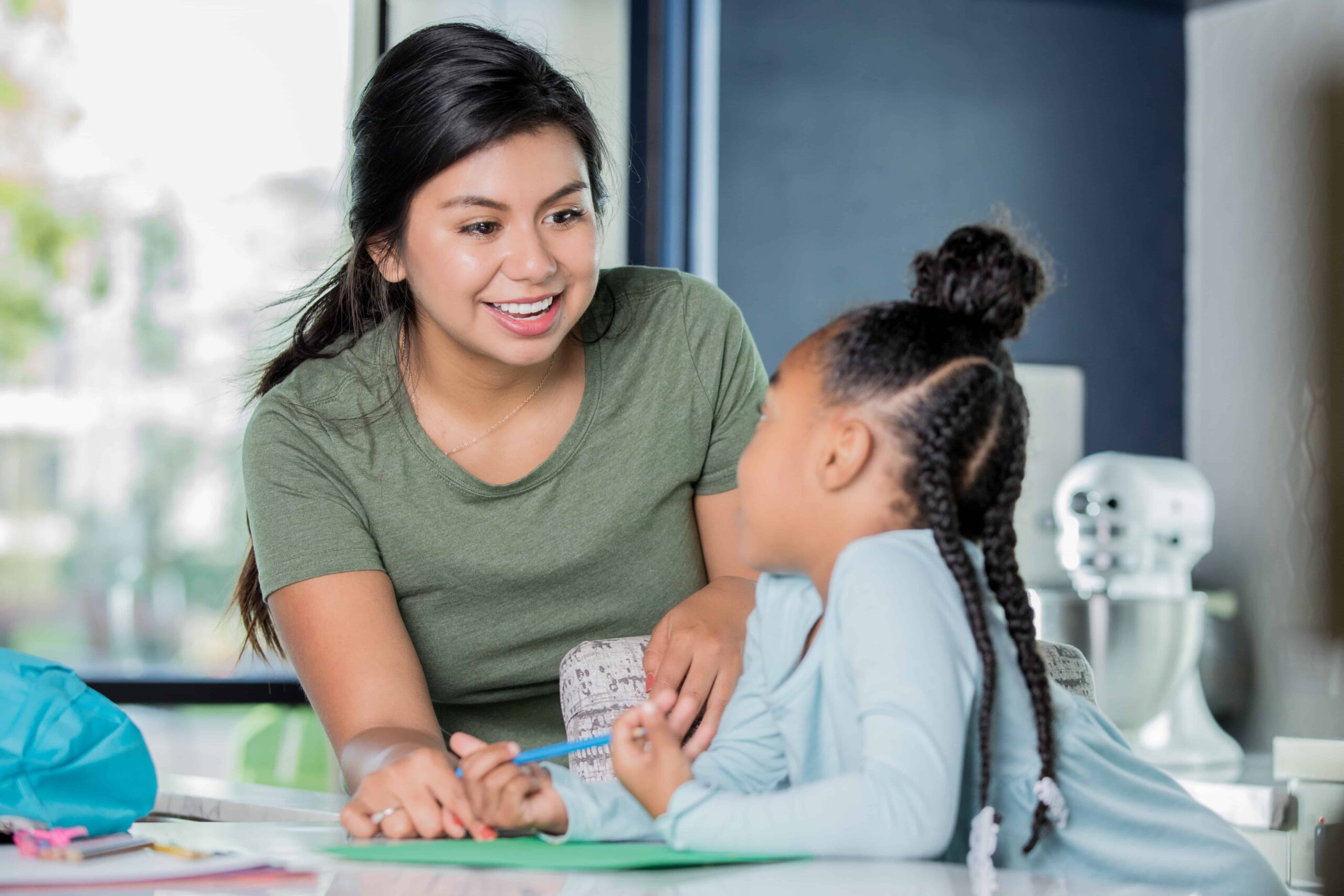 Canva - Happy young Hispanic woman is babysitting, tutoring elementary age girl.